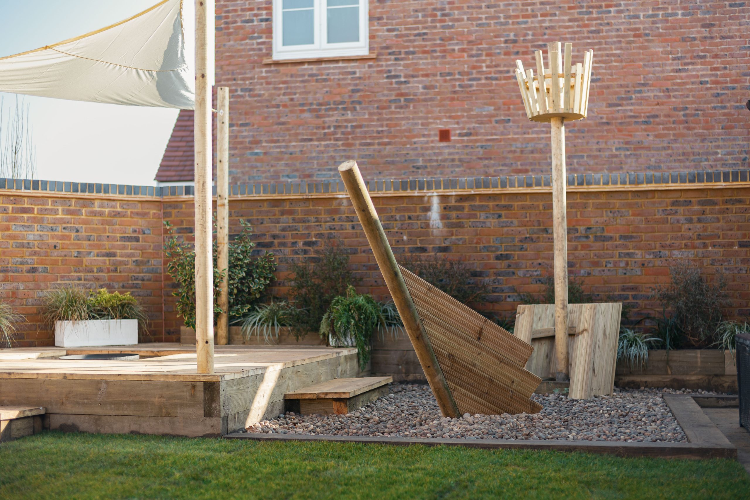 Wooden pirate ship-themed play area in Bargate Homes Rivercross garden with brick wall backdrop